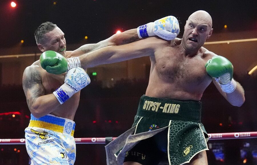 Ukrajinský šampion těžké váhy Oleksandr Usyk (vlevo) v ringu útočí na obrovitého Tysona Furyho.